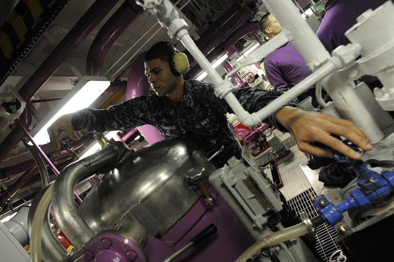 US Navy 101218-N-8040H-139 Aviation Boatswain's Mate (Fuel) Airman Apprentice Jermaine Thornton turns valves to add water to a purifier aboard USS