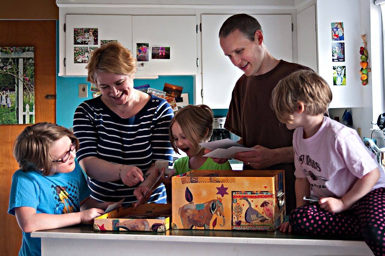 A family gathered in the kitchen at home looking at photographs