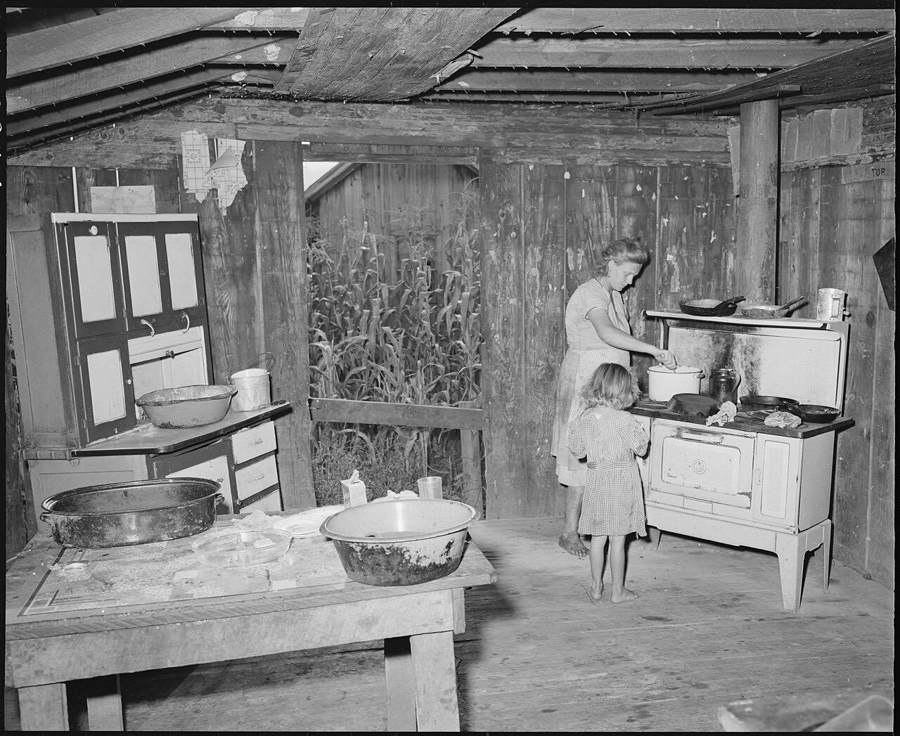 Mrs. Monroe Jones in the kitchen of the four room house which serves as the family's home and for which they pay...